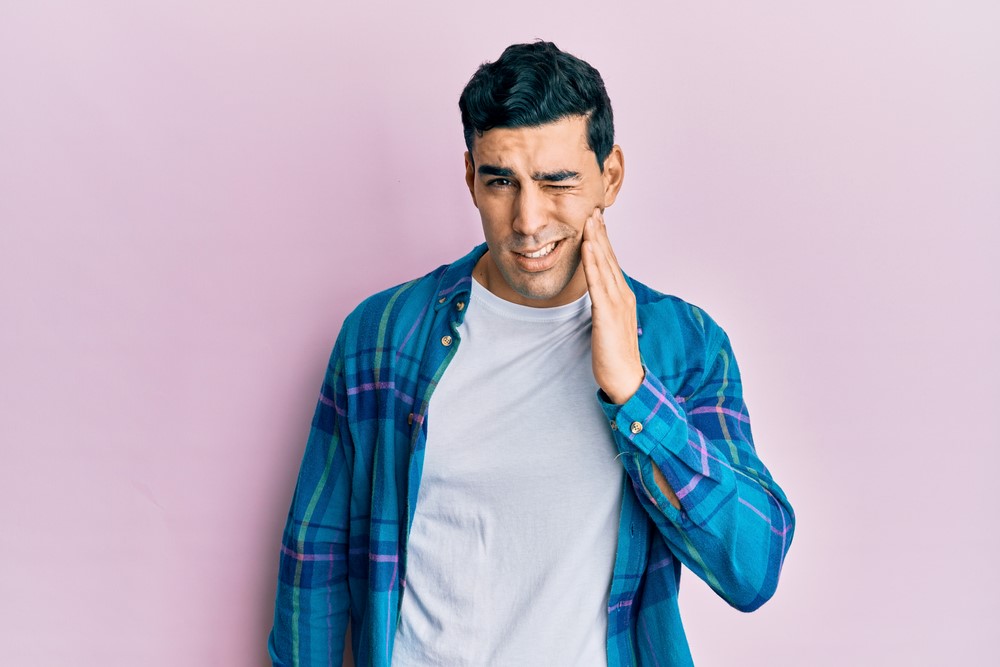 Male holding his jaw in dental pain.